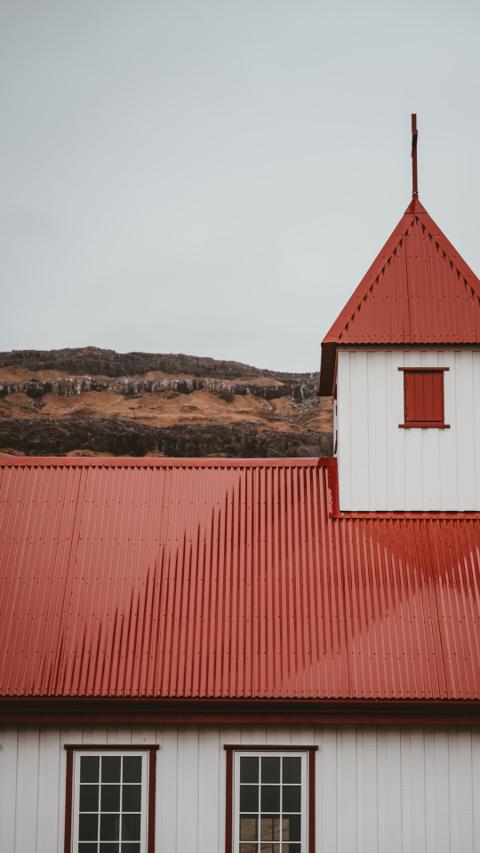 Gebäude mit rotem Blechdach in ländlicher Umgebung – Beispiel für Spenglerarbeit am Dach